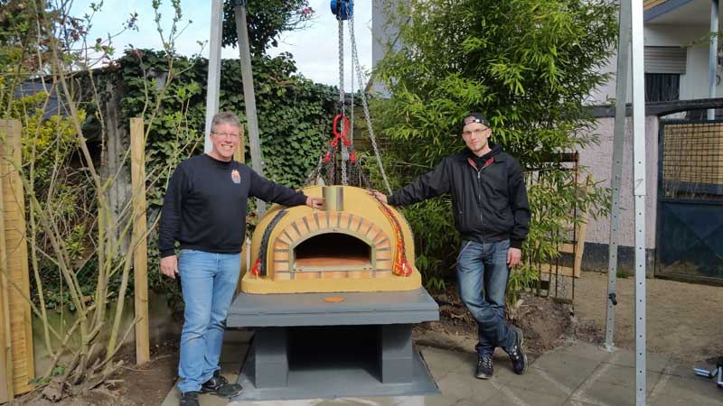 Holzbackofen über schmalen Weg in den Garten gebracht