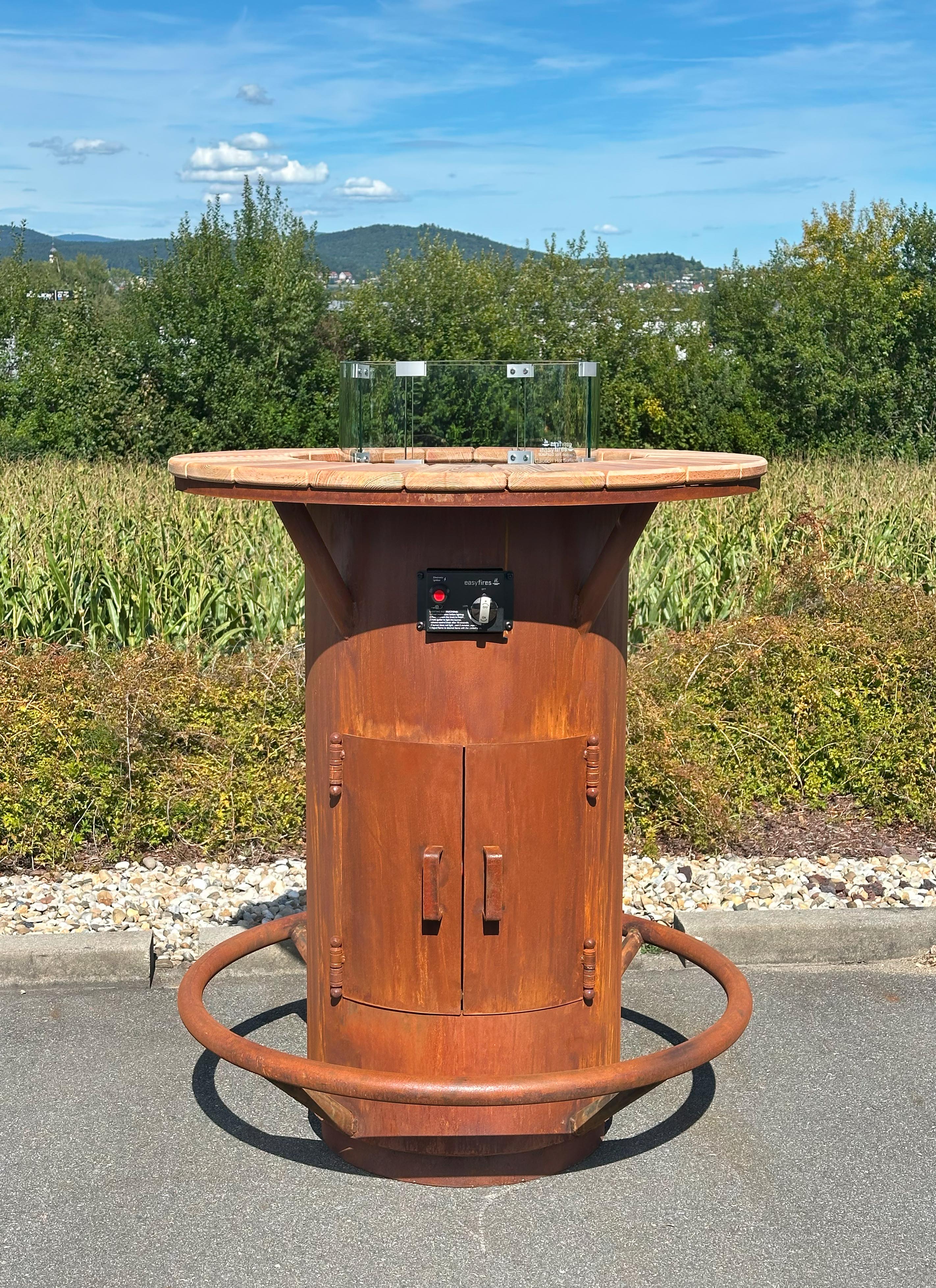Stehtischofen Ambiente Gasfeuer aus Edelrost in Seitenansicht mit runder Holzauflage
