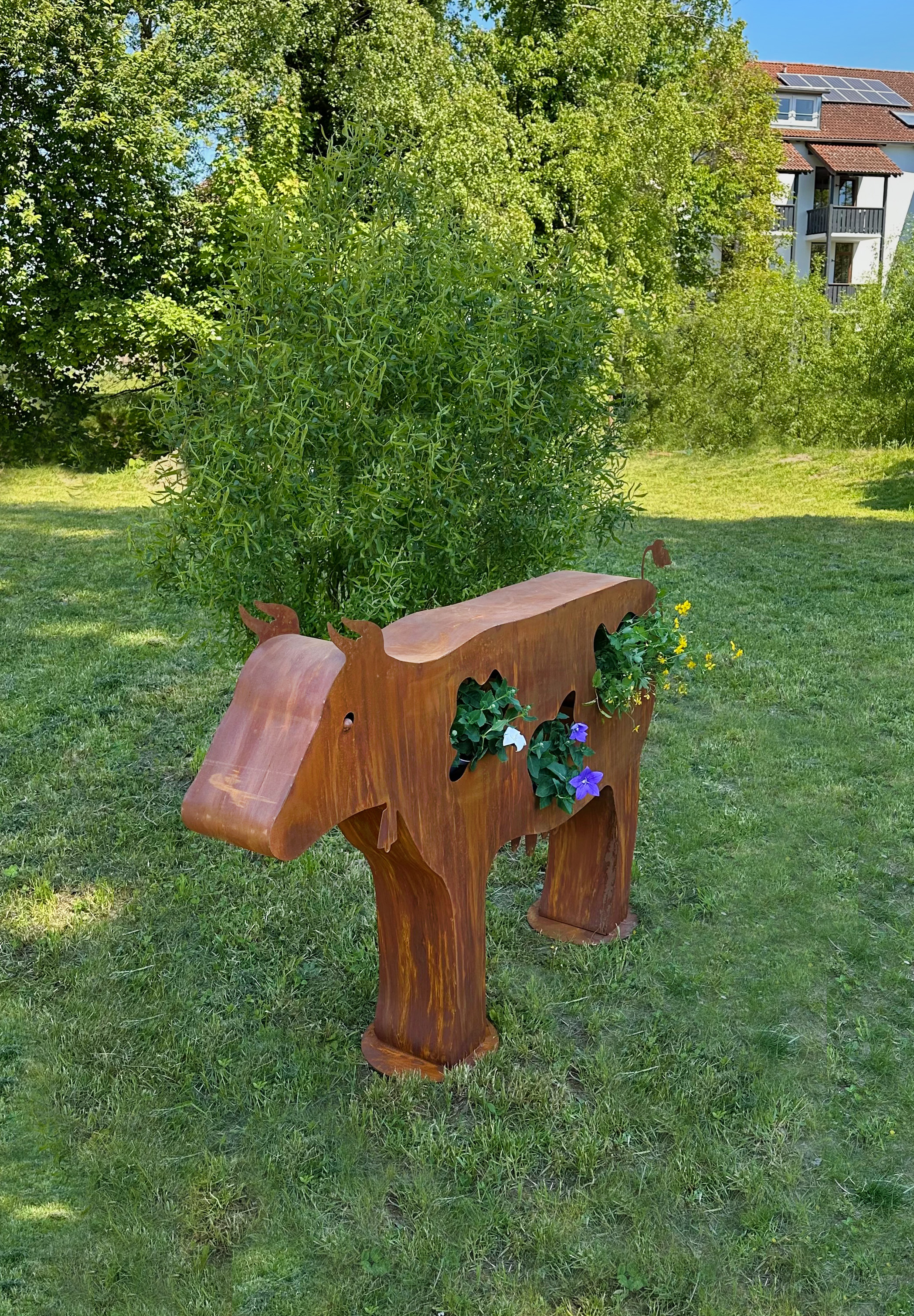 Bepflanzte Kuh Berta aus Edelrost mit Blumen als Blickfang im Garten