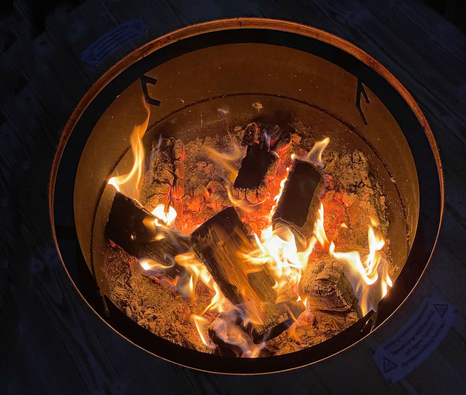 Brennende Grill-Feuerstelle Freiburg aus Edelrost mit Holzfeuer und warmem Flammenspiel
